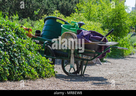 Un giardino carrello con una scopa, rastrello, annaffiatoio e secchi in giardino botanico a Wroclaw in Polonia. Foto Stock