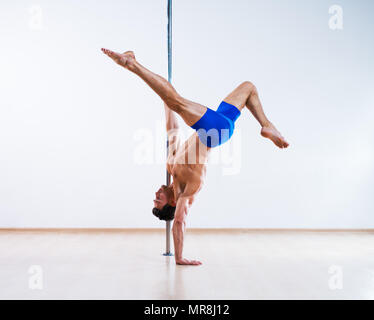 Giovani pole dancing uomo sul muro bianco sullo sfondo Foto Stock