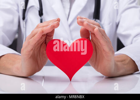 Close-up di un medico della mano rosso di protezione forma di cuore Foto Stock