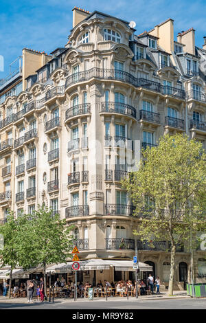 Un tipico appartamento di Parigi edificio con intricati dettagli e ferro battuto con un piccolo caffè che occupa il livello di massa. Foto Stock