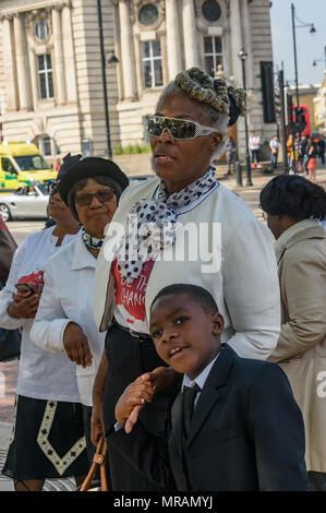 Londra, Regno Unito. 26 Maggio, 2018. Persone di ascoltare come un coro canta alla Brixton La Chiesa Avventista del Settimo Giorno 'Essere il cambiamento' evento in Piazza Windrush, Brixton contro la pistola e il coltello della criminalità. Essi avevano marciato la breve distanza della piazza della chiesa e sono state appena iniziando un programma di canto gospel, presentazioni e la preghiera per la comunità e per coloro che sono colpiti da questi crimini. Londra il tasso di omicidi è aumentata di oltre un terzo negli ultimi tre anni e lo scorso anno ha visto un aumento del 22% registrato nella criminalità coltello e 11% nella pistola criminalità. Credito: Peter Marshall / Alamy Live News Foto Stock