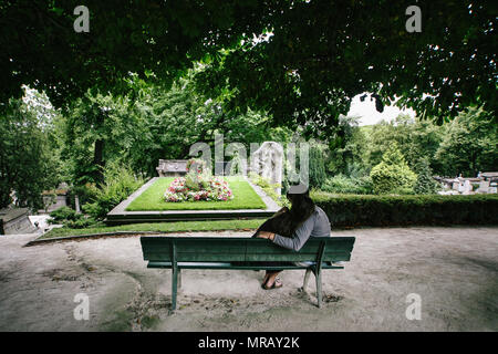 Un giovane si siede su una panchina costeggiata a Pere Lachaise, Parigi, Francia Foto Stock