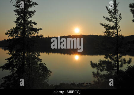 I riflessi del sole sul lago Saganagons in Quetico Foto Stock