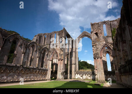 Architettura con alti archi gotici all'interno delle rovine del monastero di Fountains Abbey, Ripon, Regno Unito Foto Stock