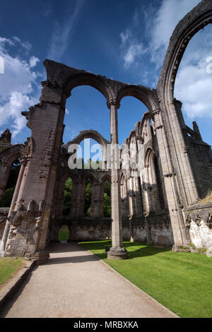 Architettura con alti archi gotici all'interno delle rovine del monastero di Fountains Abbey, Ripon, Regno Unito Foto Stock