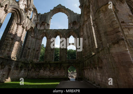 Architettura con alti archi gotici all'interno delle rovine del monastero di Fountains Abbey, Ripon, Regno Unito Foto Stock