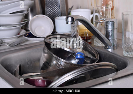 Un enorme pila di piatti non lavati nel lavello da cucina e sul bancone. Un sacco di utensili e apparecchi da cucina prima del lavaggio. Il concetto di dail Foto Stock