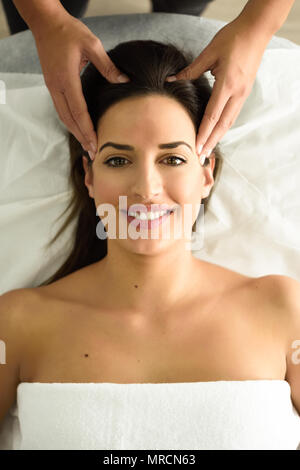 Vista dall'alto di giovani caucasici donna sorridente ricevere un massaggio della testa in un centro termale. Paziente di sesso femminile è di ricevere il trattamento dal terapista professionale. Foto Stock