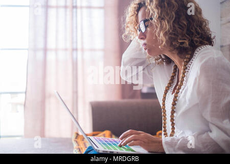 Annoiato e stanco donna caucasica la gente che lavora a casa con computer portatile e connessione internet. Bellissimo modello libertà fare business senza ufficio abituale. Foto Stock