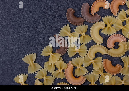 Varietà di tipi di pasta italiana sullo sfondo. Set di materie pasta secca su un nero ardesia sfondo. Foto Stock