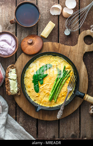 Frittata con asparagi verdi, pisello in padella, vista dall'alto, in stile rustico. Foto Stock