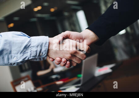 Due gestori in abbigliamento casual in sala riunioni strette di mano dopo aver trovato compromesso Foto Stock