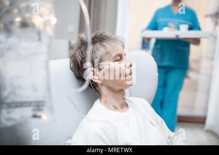 Senior donna con cannula nasale e la sacca per infusione. Foto Stock