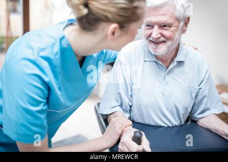 Senior uomo utilizzando rollator con cura lavoratore assistere. Foto Stock