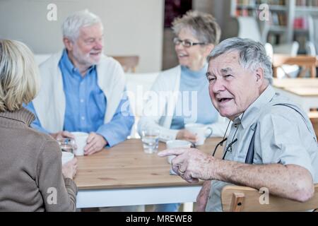 Gli amici di parlare e sorridente in casa di riposo. Foto Stock