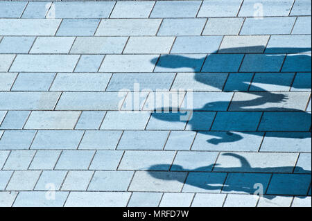 Una famiglia di tre persone a piedi in strada, appena le ombre si vede Foto Stock