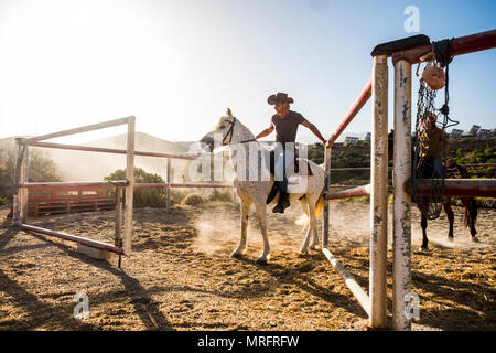 Scuola di cavallo in campagna con il bel sole di retroilluminazione e shadow. tramonto per cacuasian giovane con i cavalli migliori amici imparare ad andare. san Foto Stock