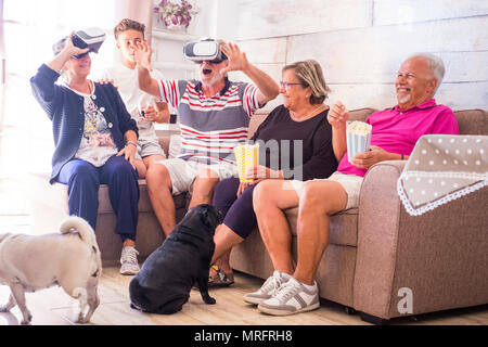 La grande famiglia tempo libero a casa con giochi di realtà virtuale gli occhiali di protezione auricolare technlogy moderno per la nuova esperienza. adulti matura nonni e adolescente nep Foto Stock