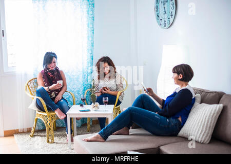 Gruppo di persone tre caucasico femmina beautifl amici rimanere a casa utilizzando cellulari smartphone insieme. tutti fare la propria attività di lavoro o tempo libero Foto Stock