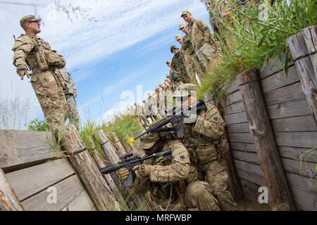 Sgt. Brett Mussyal, U.S. Soldato dell'esercito con il quarantacinquesimo della brigata di fanteria combattere Team, spiega come eliminare una trincea di soldati ukrainiens dal 1° Battaglione Airmobile, 79th Air Assault Brigade mentre U.S. Soldati dimostrano durante l assalto di trincea e un gioco di formazione presso il Yavoriv Combat Training Center sul mantenimento della pace internazionale e Centro sicurezza, vicino Yavoriv, Ucraina, il 13 giugno. Yavoriv CTC personale, insieme con le guide di U.S. Esercito della 45esima brigata di fanteria combattere la squadra, ha guidato la formazione per soldati dal 1-79th durante il battaglione di rotazione attraverso il Yavoriv CTC. Il Foto Stock