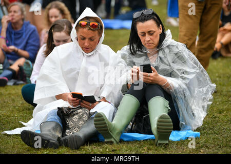 Persone indossano la pioggia ponchos in folle durante il primo giorno di BBC Radio 1's più grande weekend al Parco Singleton, Swansea. Foto Stock