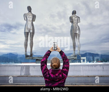 Donna turistica foto di incollamento di statue Ali e Nino con lo smartphone a Batumi, Georgia Foto Stock