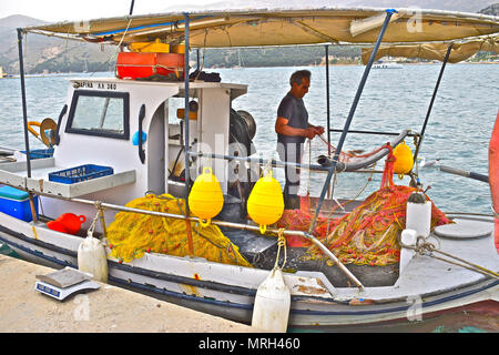 Pescatore greco riassettavano le reti a bordo la sua piccola barca nel porto della capitale Argostoli a Cefalonia / Cefalonia Grecia Foto Stock
