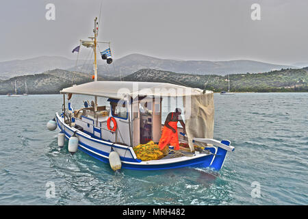 Pescatore greco l'impostazione off al mare nella sua piccola barca nel porto della capitale Argostolis in Kefalonia / Cefalonia Grecia Foto Stock