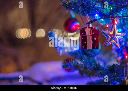 Le decorazioni di Natale su un ramo di abete, notte idillio, con neve e lampade in vari colori Foto Stock