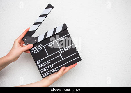 Mani femminili holding movie clapper isolato su bianco Foto Stock