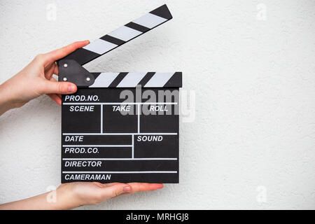 Mani femminili holding movie clapper isolato su bianco Foto Stock