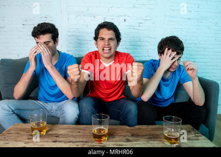 Giovane gruppo di soggetti di razza caucasica Tifosi delusi e felice di guardare una partita di calcio sul lettino. Foto Stock