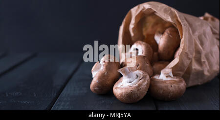 Funghi champignon in un sacchetto di carta, sullo sfondo. Spazio di copia Foto Stock