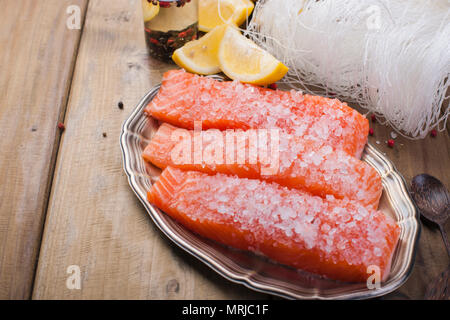 Materie filetto di salmone con pepe di animelle e sale sulla carta da forno tema rustico con copy-spazio. Foto Stock