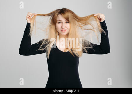 Pretty Woman holding disordinati capelli in mano. Foto Stock