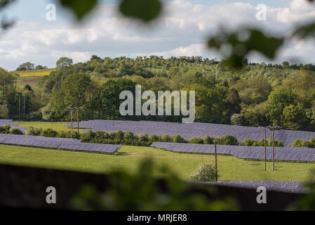 Un paesaggio trova energia alternativa pannello solare fattoria in un campo di erba ai piedi di una piccola collina. Foto Stock