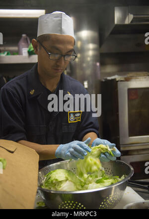 170609-N-AX638-0044 OCEANO PACIFICO 0 (Giugno 9, 2017) il capo specialista culinaria Ramon Macasaet, da Manila, Filippine, prepara il cibo a bordo della Arleigh Burke-class guidato-missile destroyer USS Howard (DDG 83). Howard è attualmente in corso da parte del vettore Nimitz Strike gruppo su una regolare distribuzione programmata per il Pacifico occidentale e indiano. (U.S. Foto di Marina di Massa lo specialista di comunicazione 2a classe Tyler Preston/rilasciato) Foto Stock