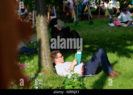 Festival di fieno, Hay on Wye, Regno Unito - Maggio 2018 - visitatori apprezzano la possibilità di sedersi e leggere sul prato del festival come il tardo pomeriggio di sole che splende sul fieno - - Photo Steven Maggio / Alamy Live News Foto Stock