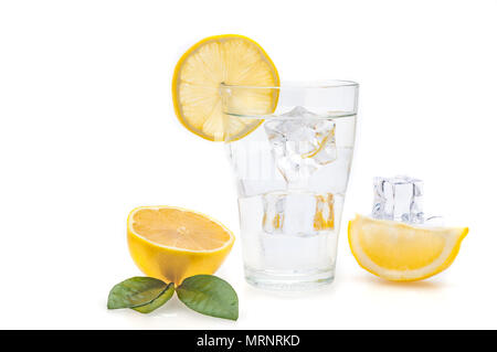 Acqua e limone e cubetti di ghiaccio in un bicchiere. Le fette di limone e lino accanto a un vetro. Foto Stock