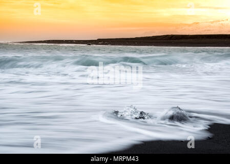 Tramonto sulla spiaggia di diamante in Islanda con lavaggio onde su gemme di ghiaccio sulla sabbia nera vulcanica beach Foto Stock