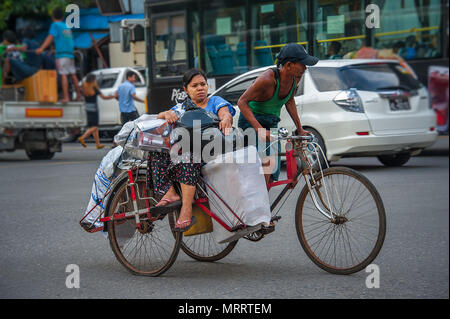 China Town, Yangon - Ott 21, 2017: un triciclo il taxi per il trasporto di un passeggero e il suo numero di sacchetti di plastica, alcuni sul suo grembo, altri sullo spazio disponibile. Foto Stock