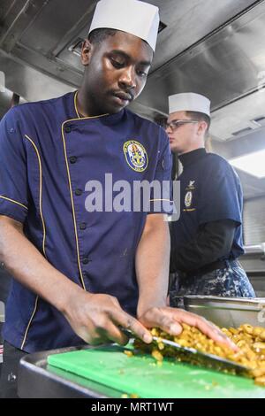 170626-N-GX781-023 OCEANO ATLANTICO (26 giugno 2017) - specialista culinaria marinaio Julian Ware, da Annapolis, Maryland, prepara il pranzo per i marinai a bordo del Arleigh Burke-class guidato-missile destroyer USS James E. Williams (DDG 95) Il 26 giugno 2017. James E. Williams, home-ported a Norfolk, Virginia, è su una distribuzione di routine per gli Stati Uniti Sesta flotta area di operazioni a sostegno degli Stati Uniti per gli interessi di sicurezza nazionali in Europa. (Marina degli Stati Uniti foto di MC3 Colbey Livingston/ rilasciato) Foto Stock