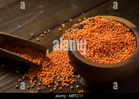 Organico sani di lenticchie rosse nella ciotola di legno scuro tabella Foto Stock