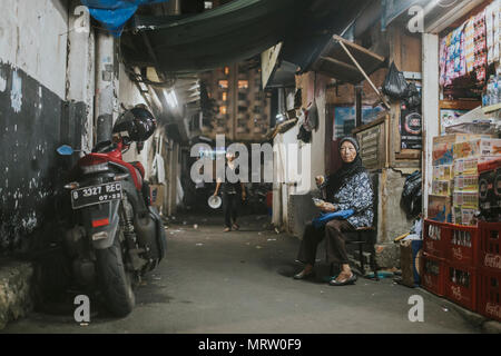 JAKARTA, Indonesia - 26 gennaio 2018: musulmano non identificato donna seduta dal suo negozio nel vicolo di Jakarta, Indonesia. Foto Stock