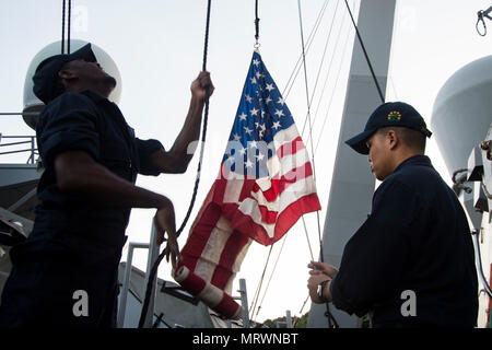 170711-N-BB269-026 Yokosuka, Giappone (11 luglio 2017) Intendente di terza classe William verde, a sinistra, e intendente di terza classe Jeric Andaya, entrambi assegnati alla Arleigh Burke-class guidato-missile destroyer USS Fitzgerald (DDG 62), alzare la bandiera americana durante la partenza della nave dalla banchina di ormeggio 12 presso le attività della flotta (FLEACT) Yokosuka. Fitzgerald è entrare in bacino di carenaggio di FLEACT Yokosuka per proseguire la riparazione e di valutare i danni subiti dalla sua Giugno 17 collisione con una nave mercantile. (U.S. Foto di Marina di Massa lo specialista di comunicazione 2a classe Raymond D. Diaz III/rilasciato) Foto Stock