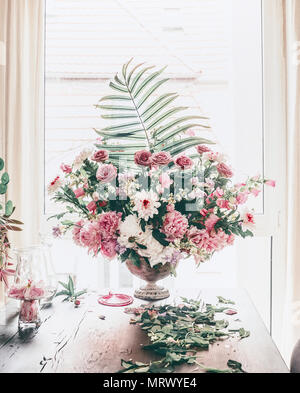 Evento di disposizione di fiori. Grande festa bouquet classico con varie specie di fiori e foglie di palmo in urna vaso sulla tabella nella finestra nel soggiorno. Holiday Foto Stock