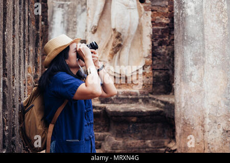 Asian tourist donna prendendo foto di antiche del tempio thailandese architettura al Sukhothai Historical Park,della Thailandia. Viaggiatori femmina in casual Mauhom thai s Foto Stock