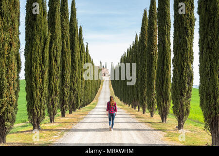 Castiglion d'Orcia, Val d'Orcia, Siena, Toscana, Italia. Una giovane donna in abiti casual è camminare lungo una strada di campagna Foto Stock