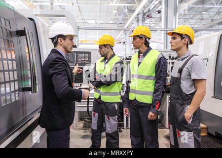 Manager e lavoratori a pianta nei pressi di macchine CNC Foto Stock