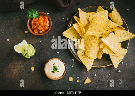 Nachos chips e varie salse dip. Tortilla di mais chip nachos con salsa di formaggio fuso e guacamole, messicani snack. Foto Stock